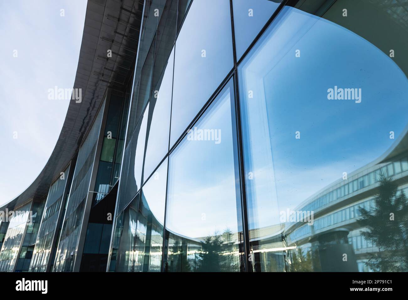 The blue sky is reflected in the windows of a modern office building ...