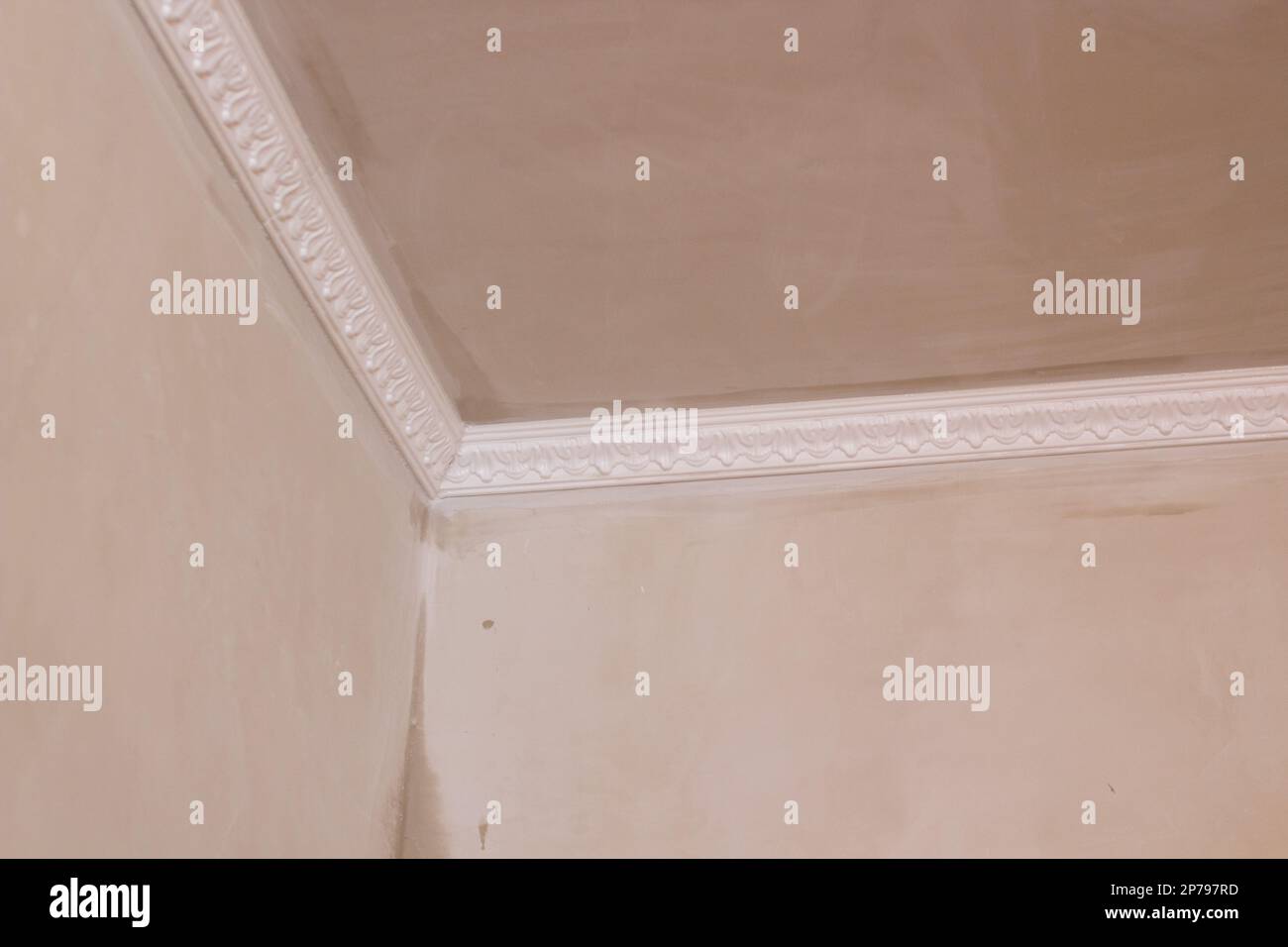 Installation of ceiling moldings. Worker puts glue on plastic molding