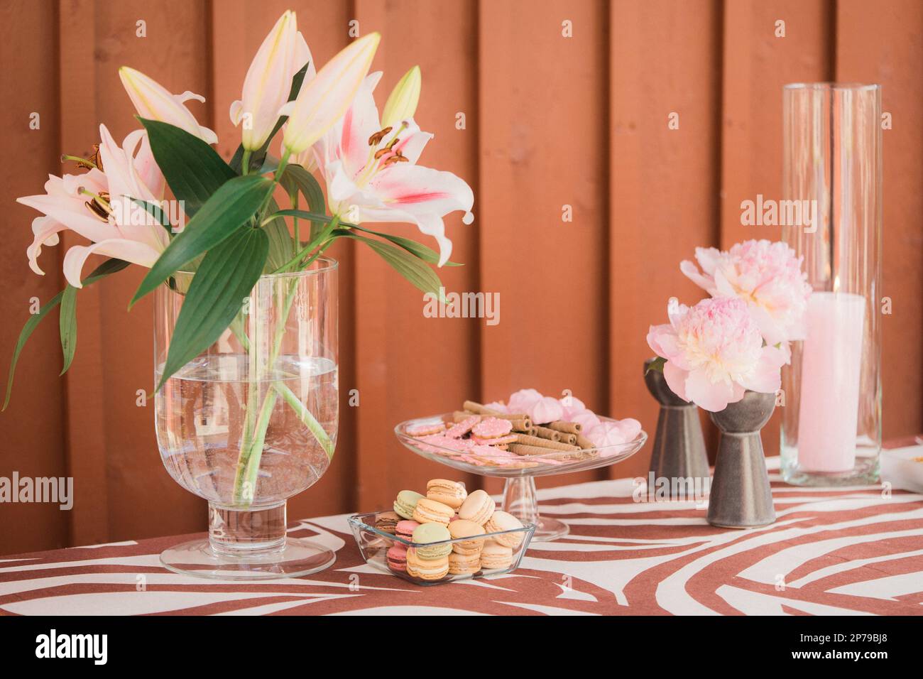 Lily flowers in glass vase and macaroons on table Stock Photo