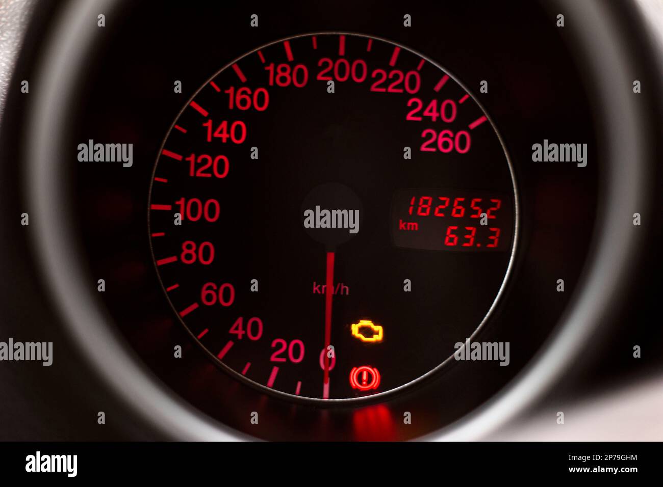 Car dashboard speedometer with check engine light symbol glowing red