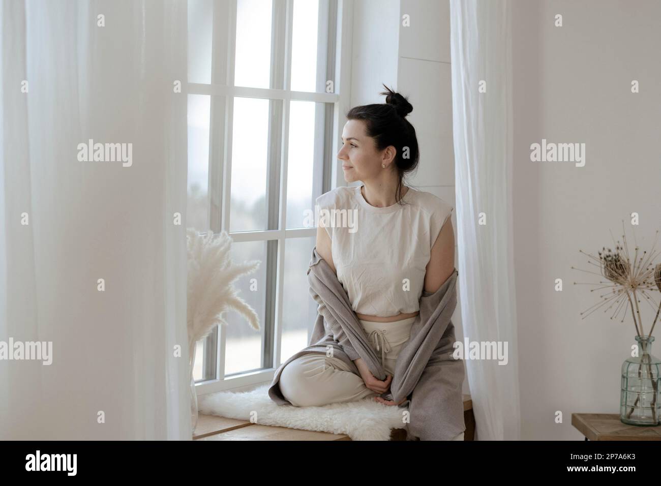 Dark-haired woman sits relaxed at the window Stock Photo