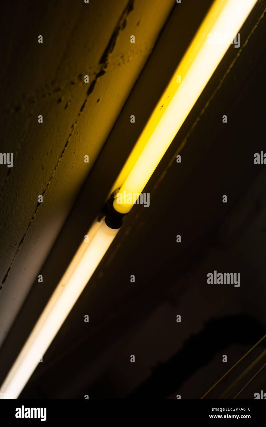 Old defective flickering yellow neon lights ceiling mounted inside dark