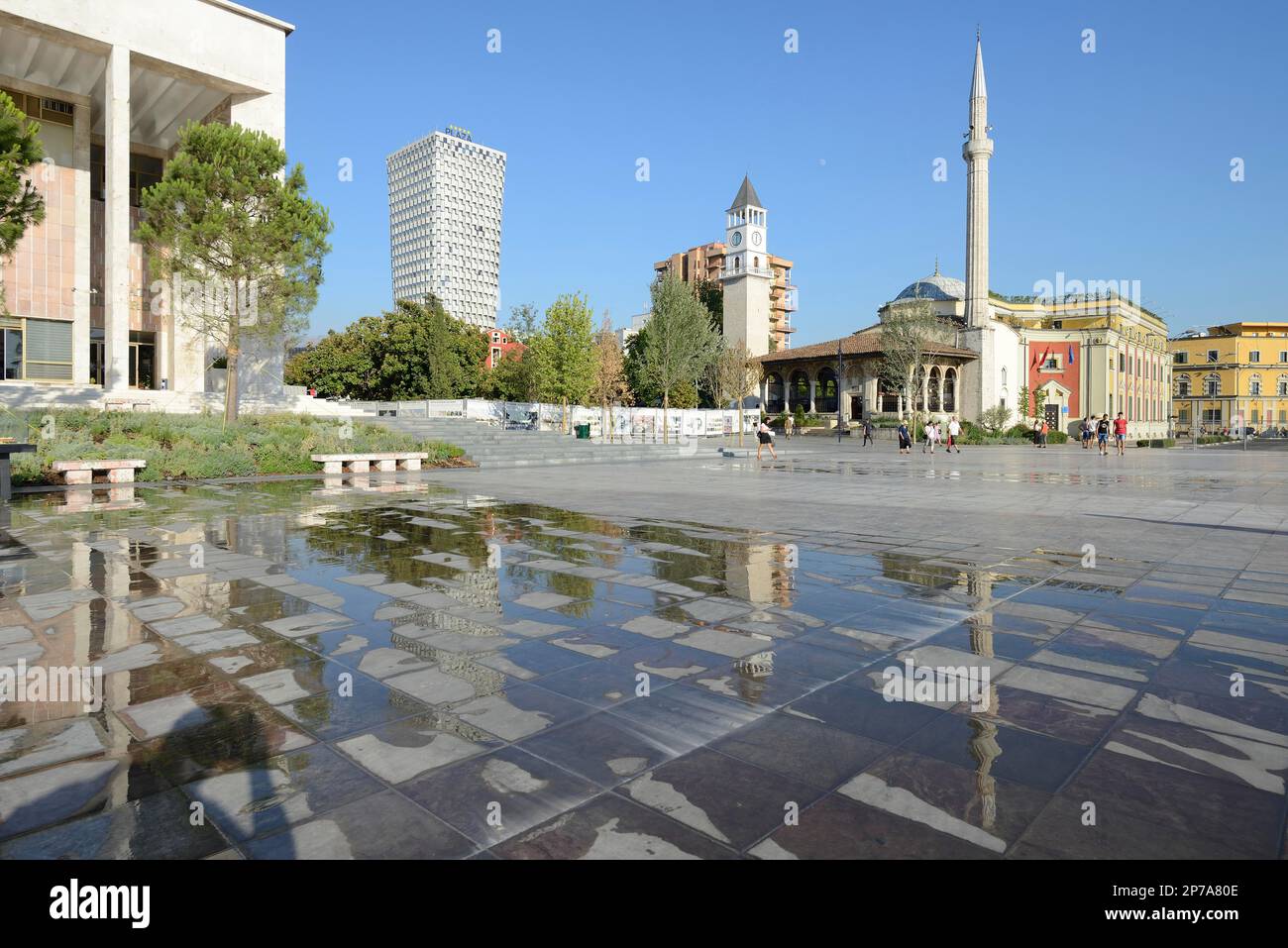 Plaza Hotel, Bell Tower and Ethem Bey Mosque reflected in a puddle, Skanderbeg Square, Tirana, Albania Stock Photo
