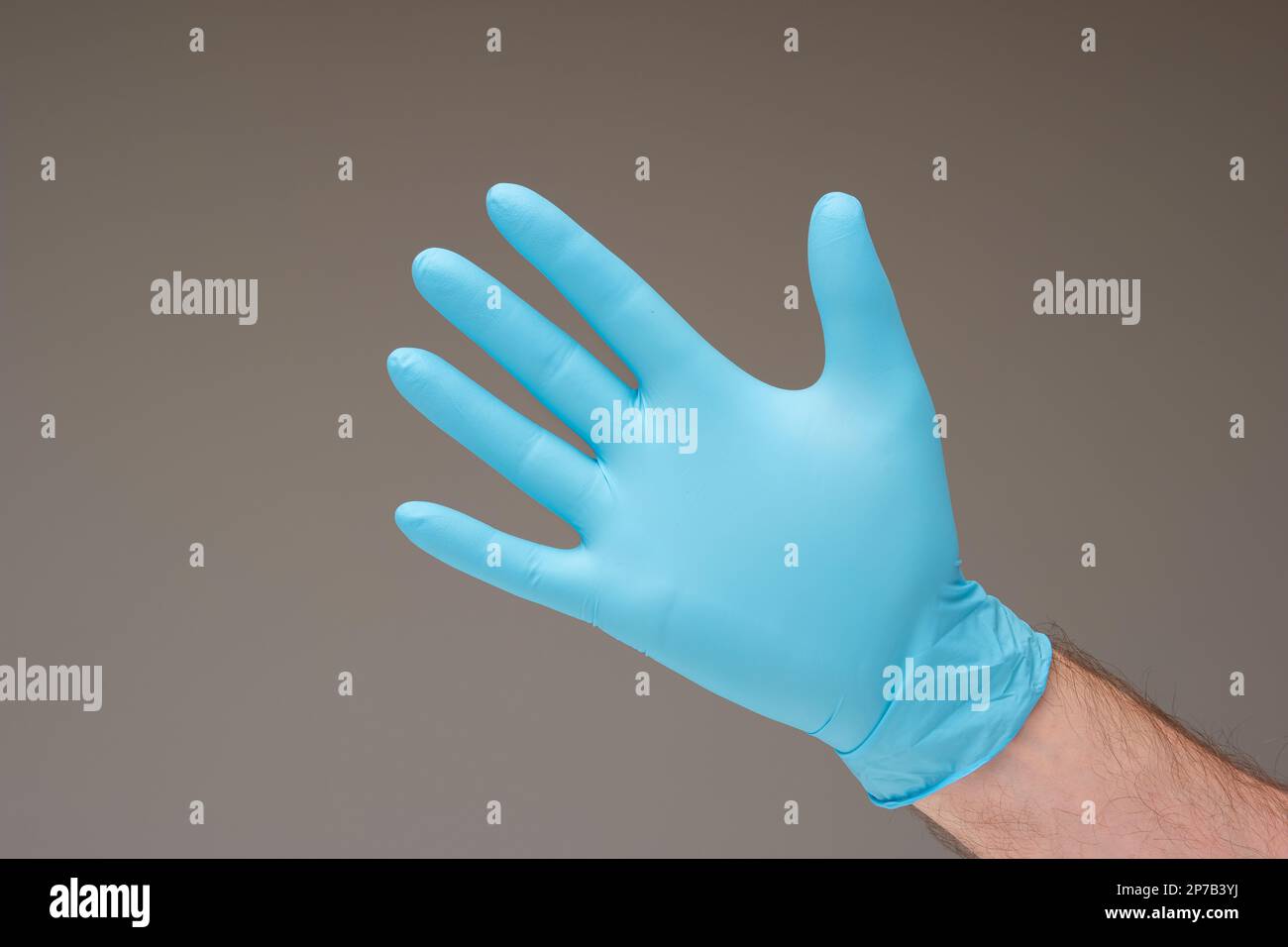 Disposable blue latex glove worn by Caucasian male hand. Close up