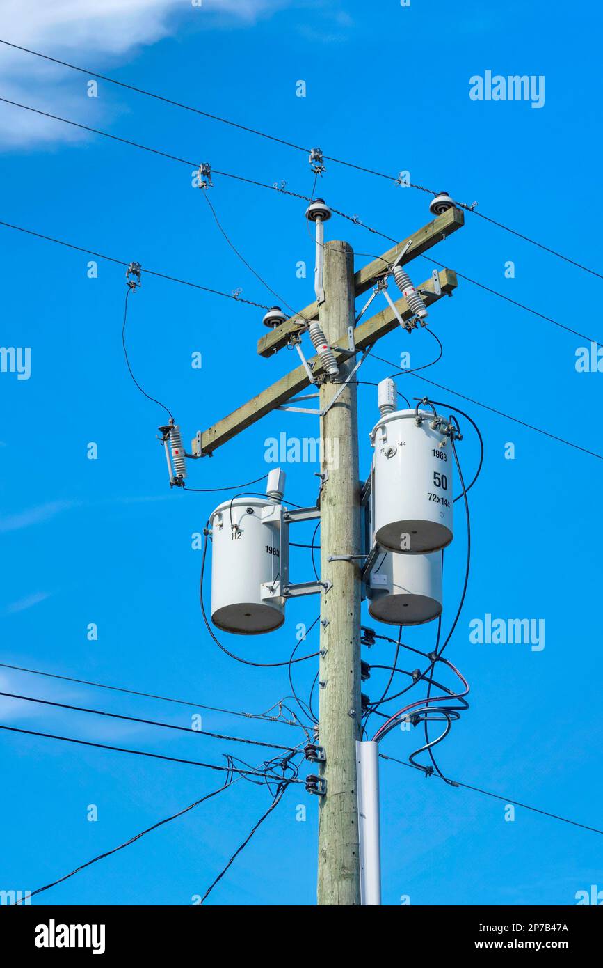 Wooden electricty pole with mounted transformators on blue sky background  Stock Photo