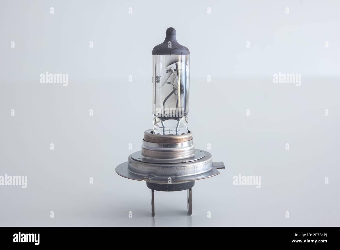 Burned H7 12V 55W halogen car light bulb. Close up studio shot, isolated on white, no people. Stock Photo