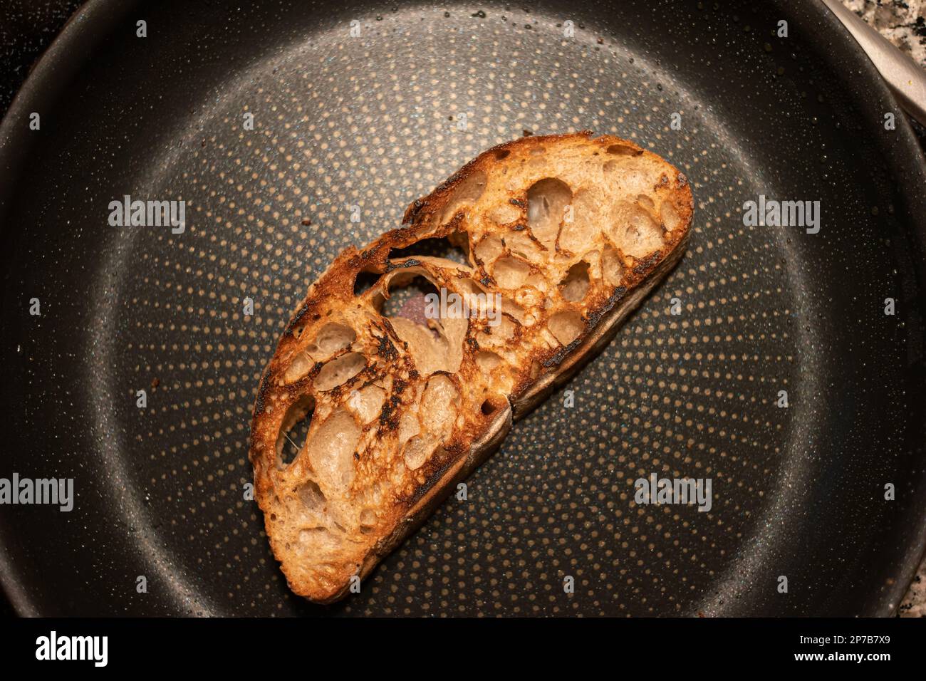 Toasting a slide of bread in a frying pan. Top view, no people, close