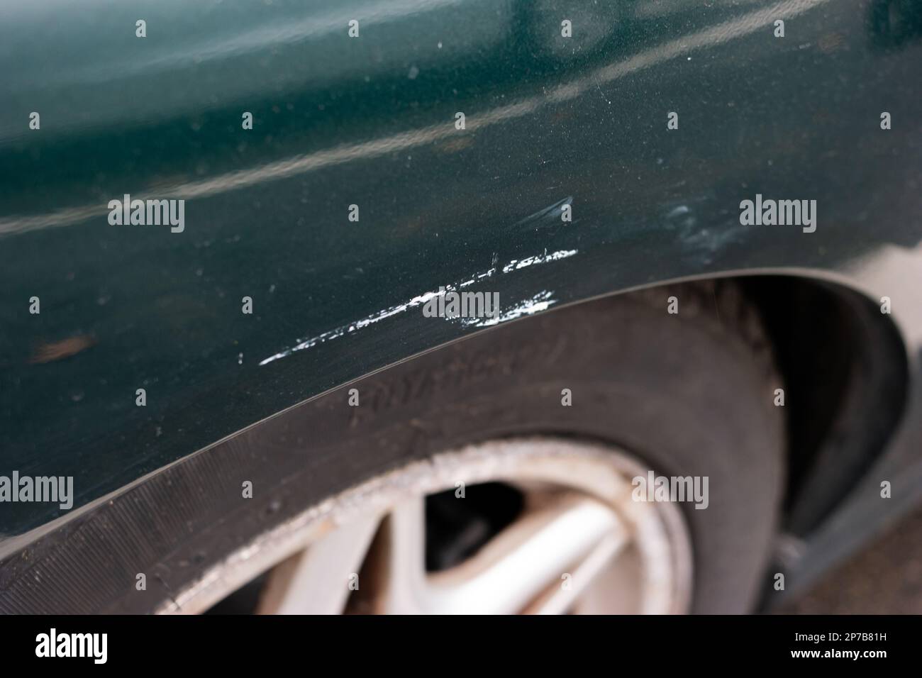 Car wheel arch paint damage. Small scratch white pant transfer from parking space poll. Close up