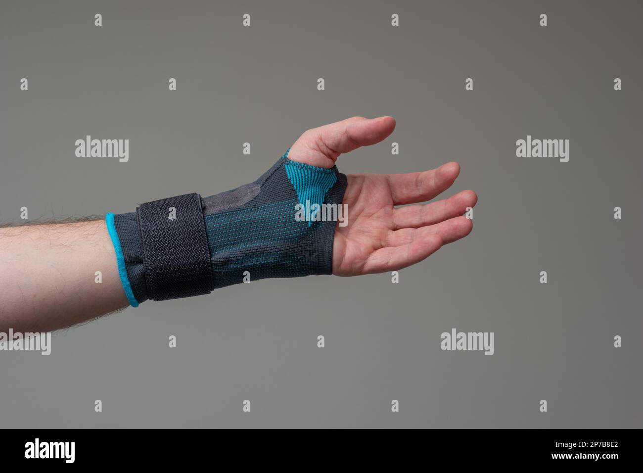 Velcro wrist stabilizer cast worn by Caucasian male hand. A blue split brace meant to aid Carpel