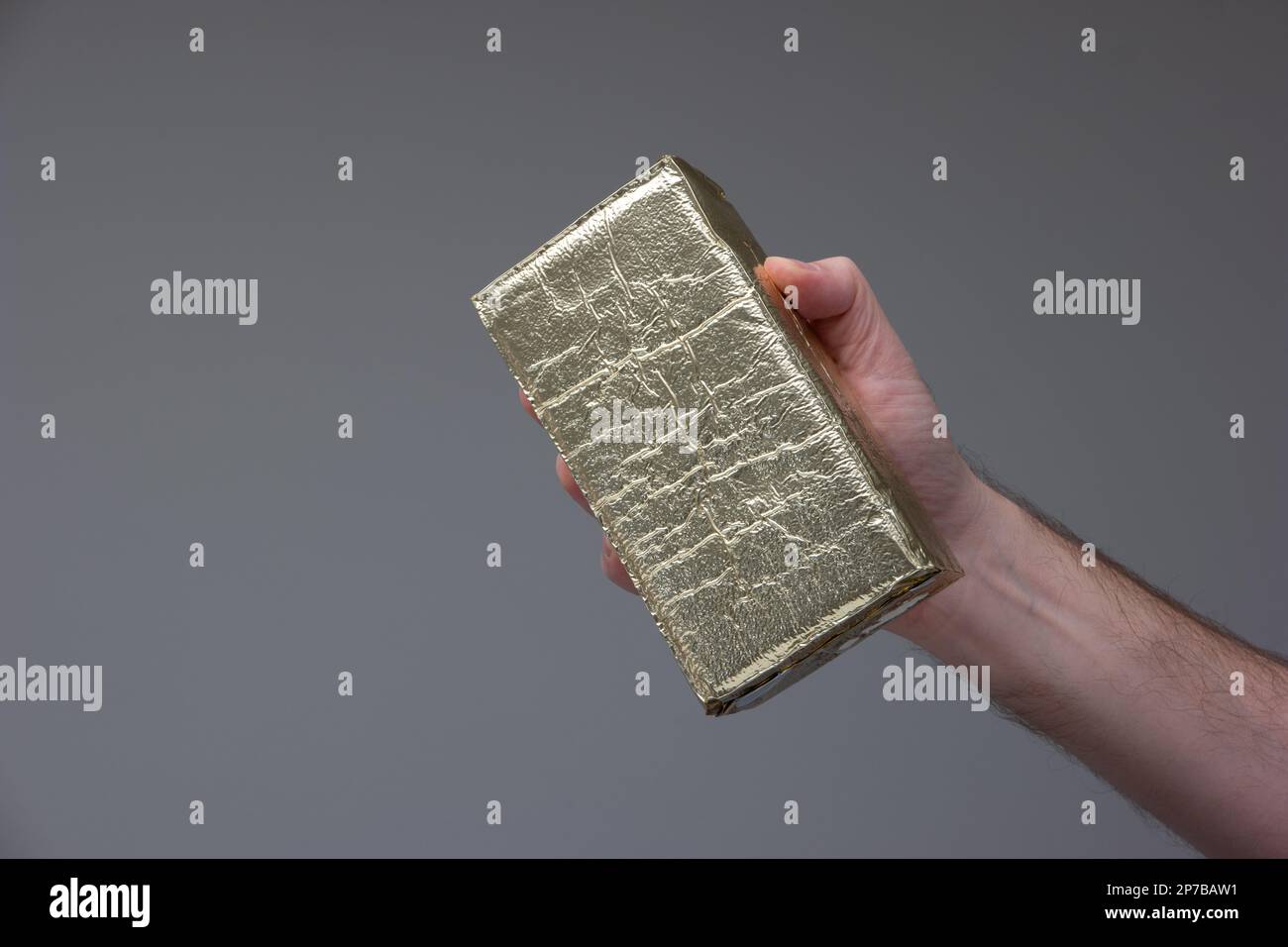 Gold foil vacuum sealed coffee brick held in hand by Caucasian male