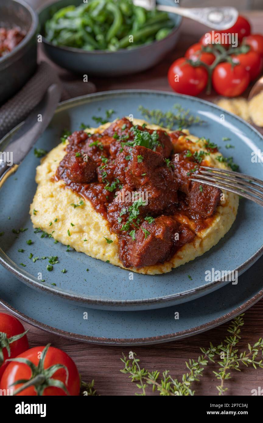Meat dish for sunday or holiday with a delicious italian pork ragout, creamy polenta and green beans on a plate Stock Photo
