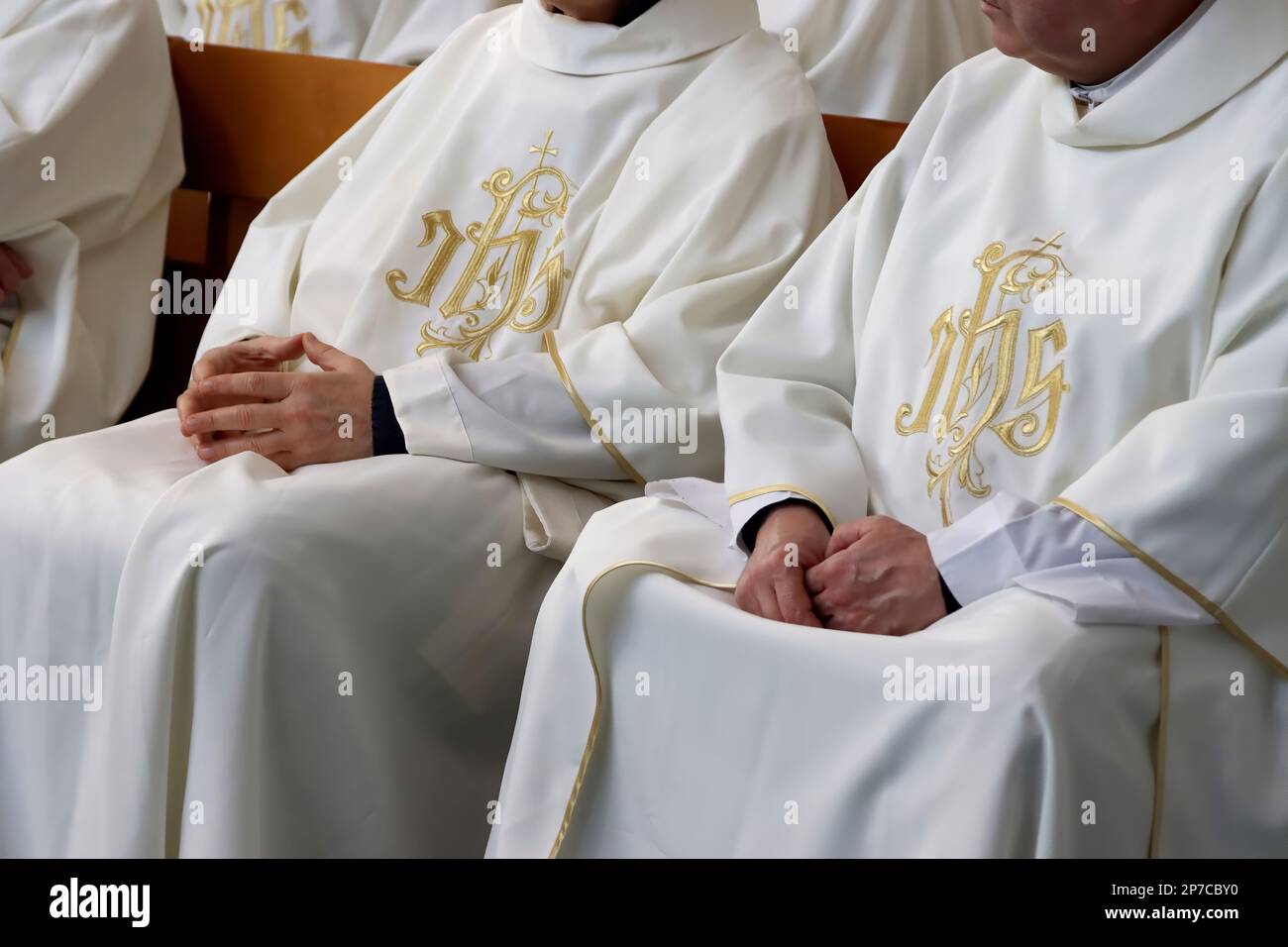 Two Catholic priests sitting on a church pew during Sunday mass Stock Photo