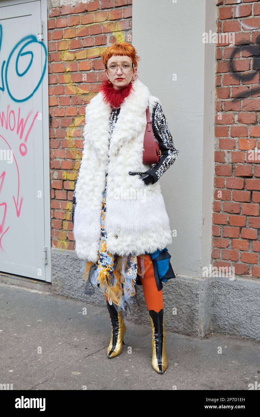 MILAN, ITALY - FEBRUARY 22, 2023: Woman with white fur coat and golden and black boots before Fendi fashion show, Milan Fashion Week street style Stock Photo