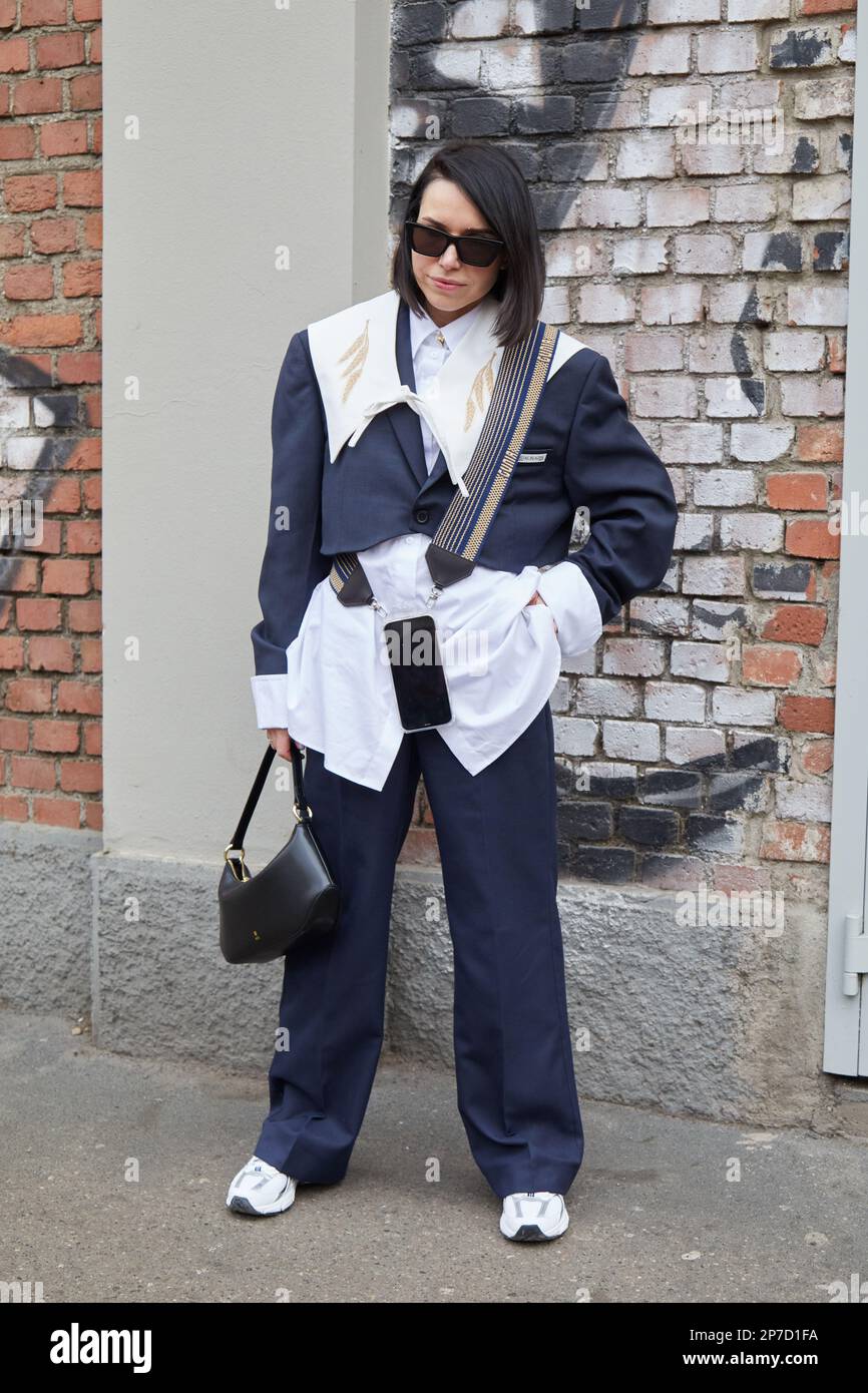 MILAN, ITALY - FEBRUARY 22, 2023: Woman with white shirt, blue trousers and jacket before Fendi fashion show, Milan Fashion Week street style Stock Photo