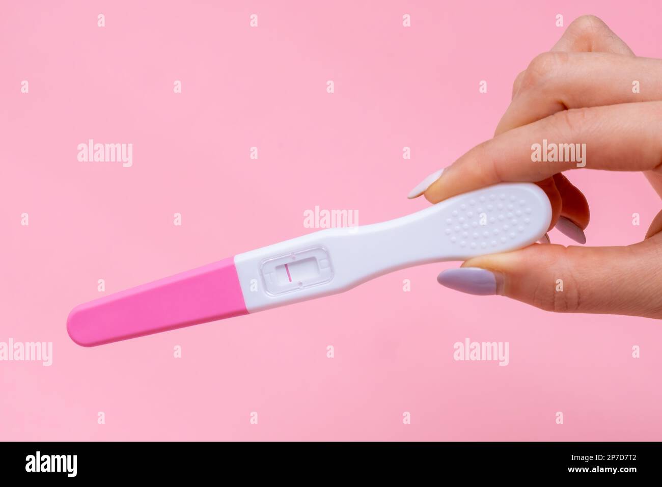 Womans hand holding negative pregnancy test with one stripe on pink ...