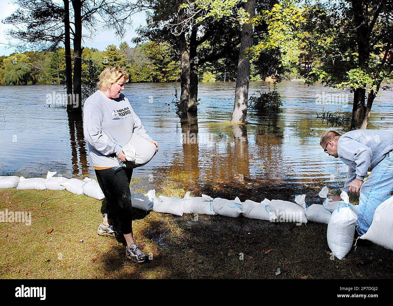 Jami Tralmer, left, of Eau Claire, Wis. carries a sand bag Saturday