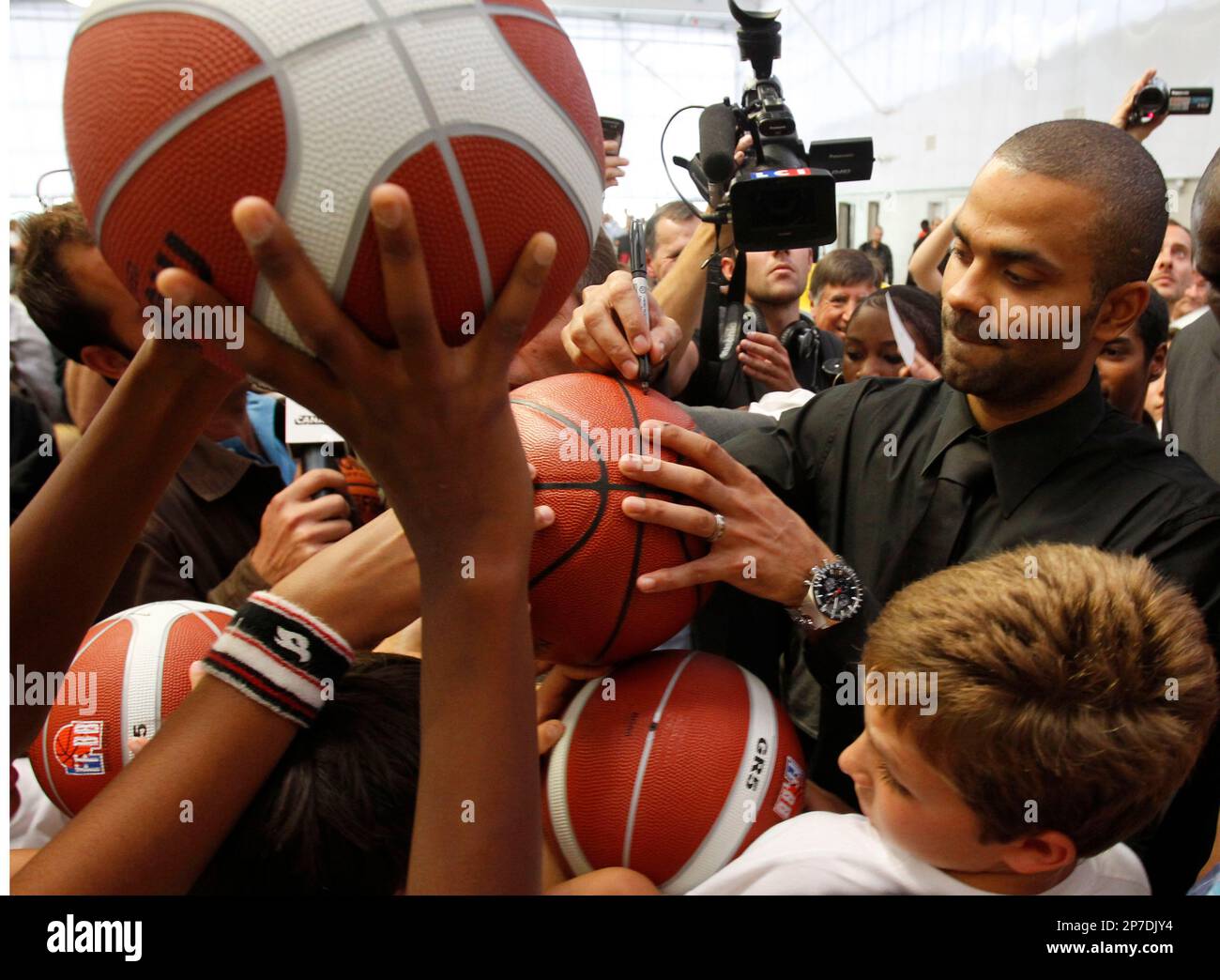 French NBA San Antonio Spurs player Tony Parker signs basketballs as he