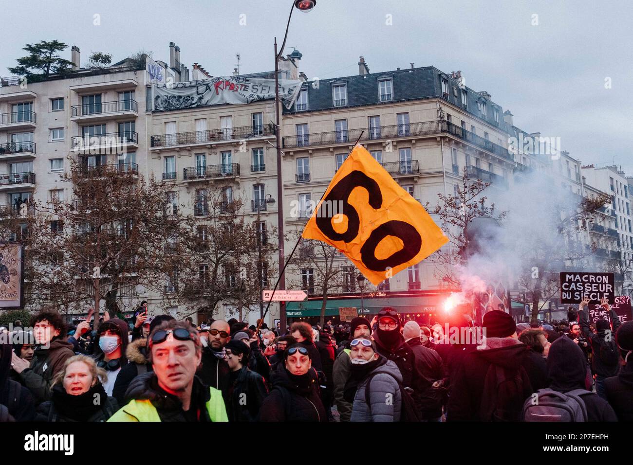 France / Paris / 07/03/2023, Jan Schmidt-Whitley/Le Pictorium -  Demonstration against pension reform in Paris  -  7/3/2023  -  France / Paris / Paris  -  A demonstrator carries a flag calling for retirement at 60. Even if the number of strikers did not reach January's records, the unions hailed a 'historic mobilisation' on Tuesday 7 March, during demonstrations that brought together 1.28 million people in France, according to the Ministry of the Interior, and 3.5 million, according to the CGT. Stock Photo