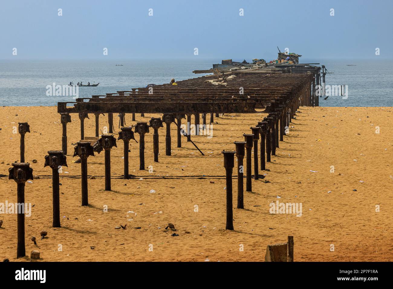 a row of metal supports on the sandy beach in lome leading out into the atlantic ocean are part of the derelict old pier Stock Photo