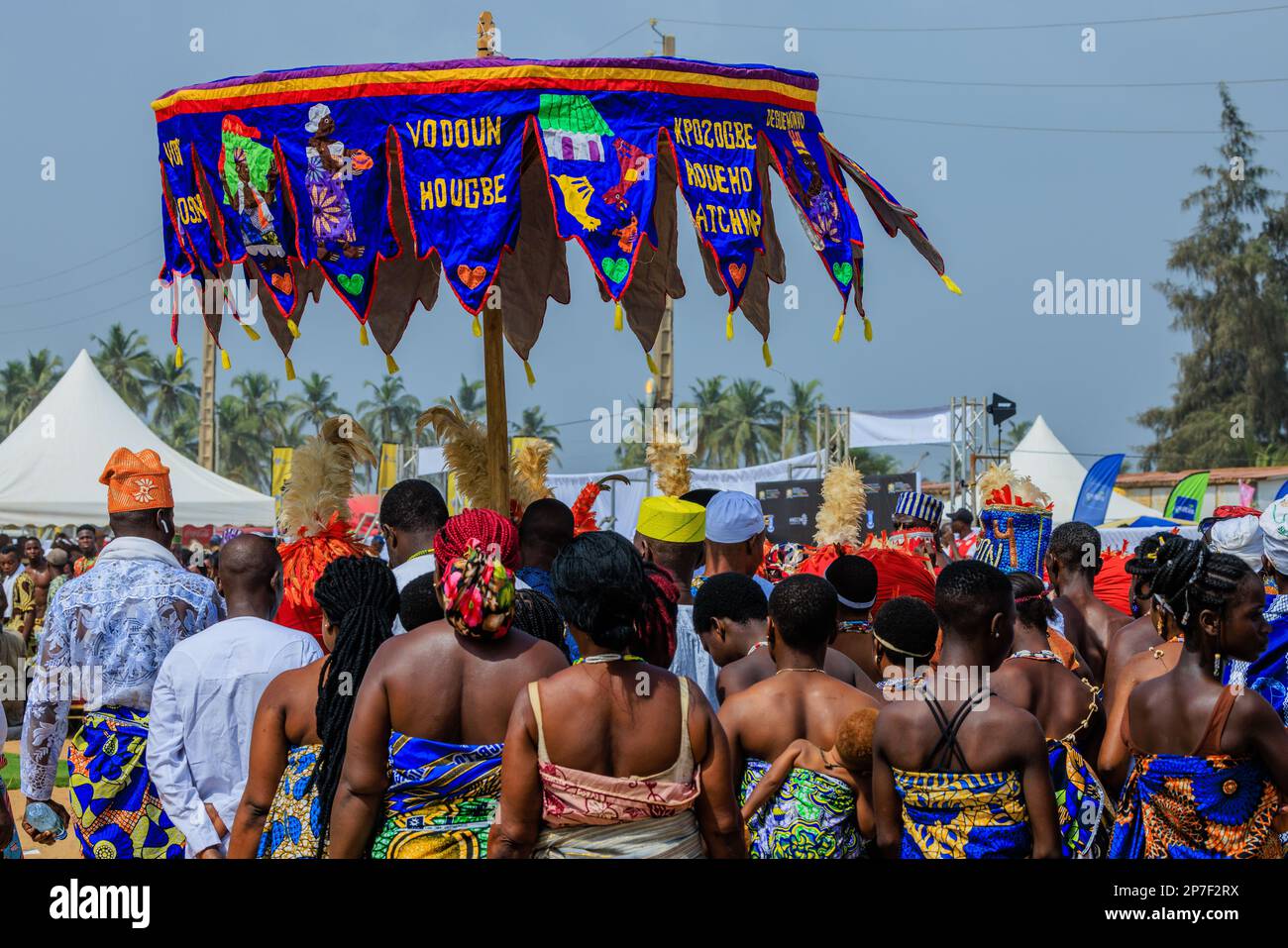 procession of followers of a voodoo temple under their banner umbrella at the beach parade
