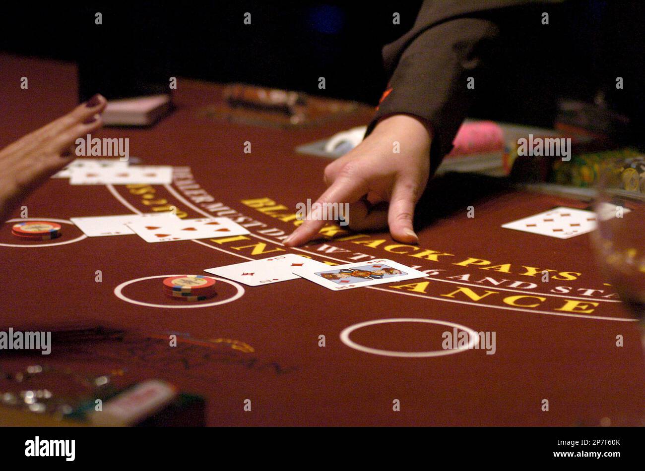 A gambler stands as the dealer points to a card at a Blackjack table on