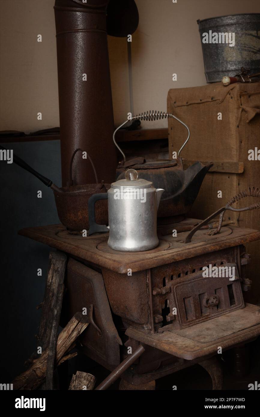 A coffee pot, kettle, and pan on an old wood stove. Stock Photo