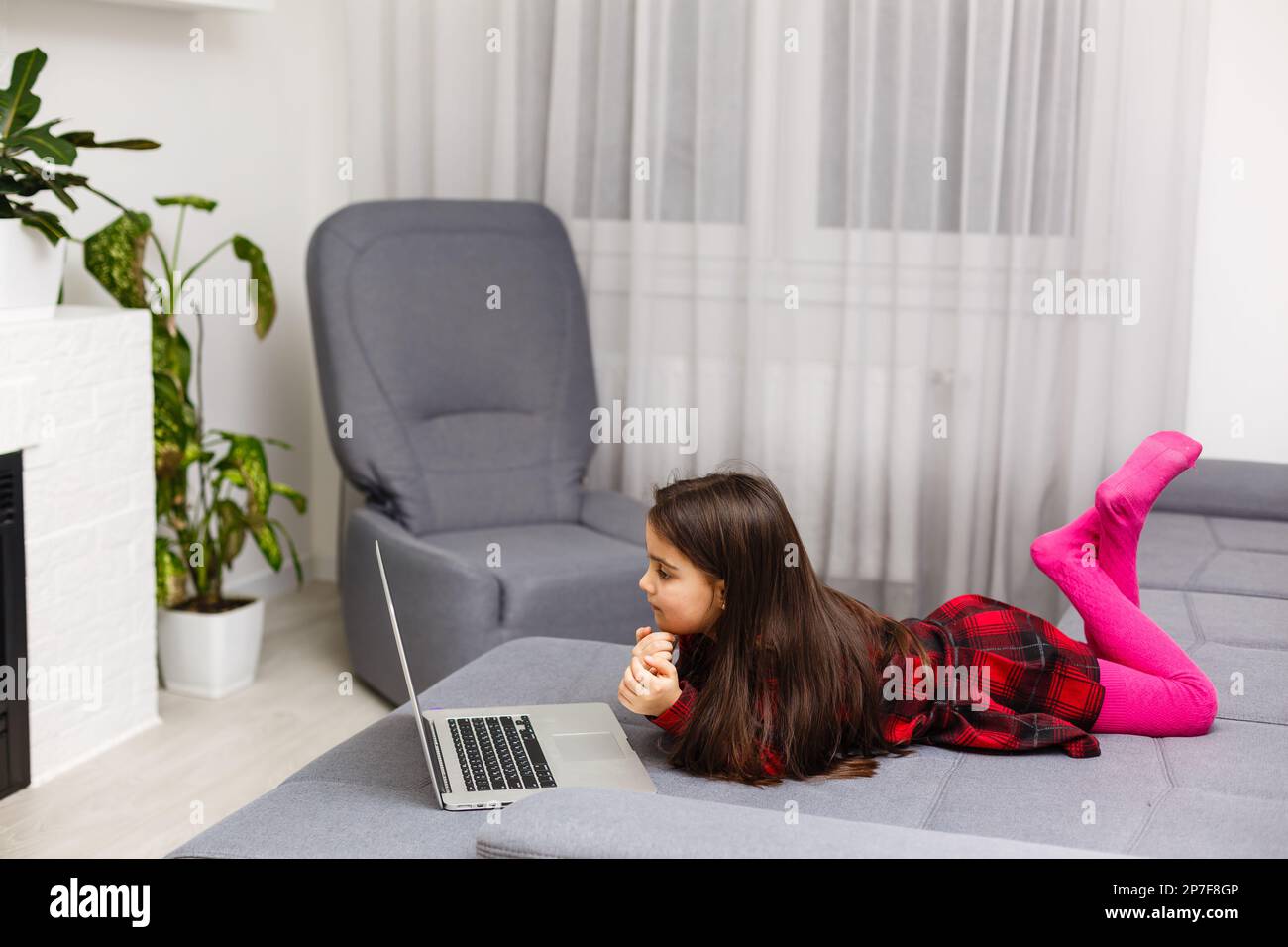 Happy little girl at home working with a laptop Stock Photo - Alamy