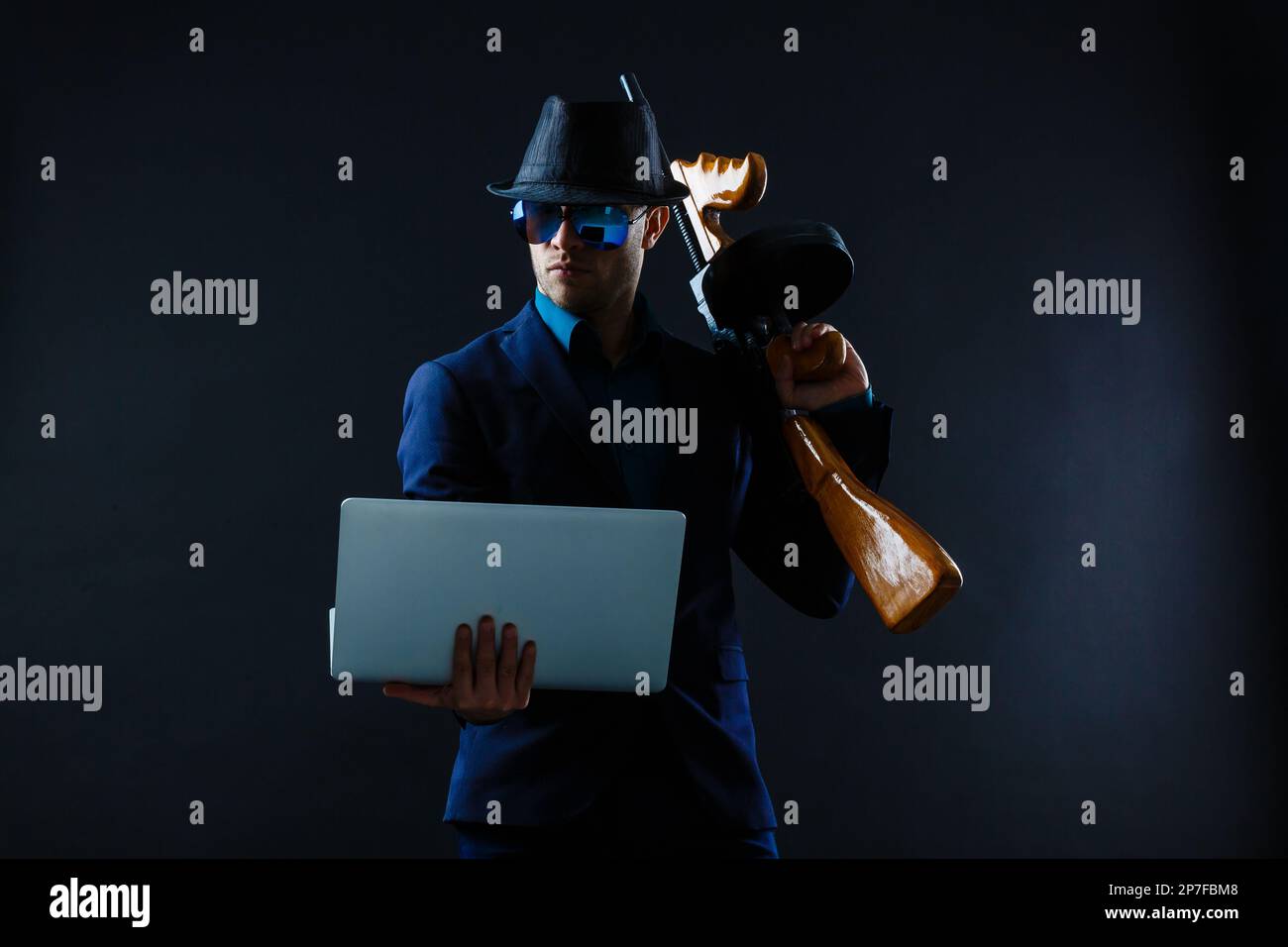 businessman in sunglasses with machine gun and laptop Stock Photo Alamy