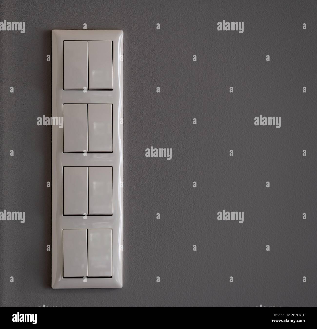 Eight white light switches on a grey wall Stock Photo Alamy