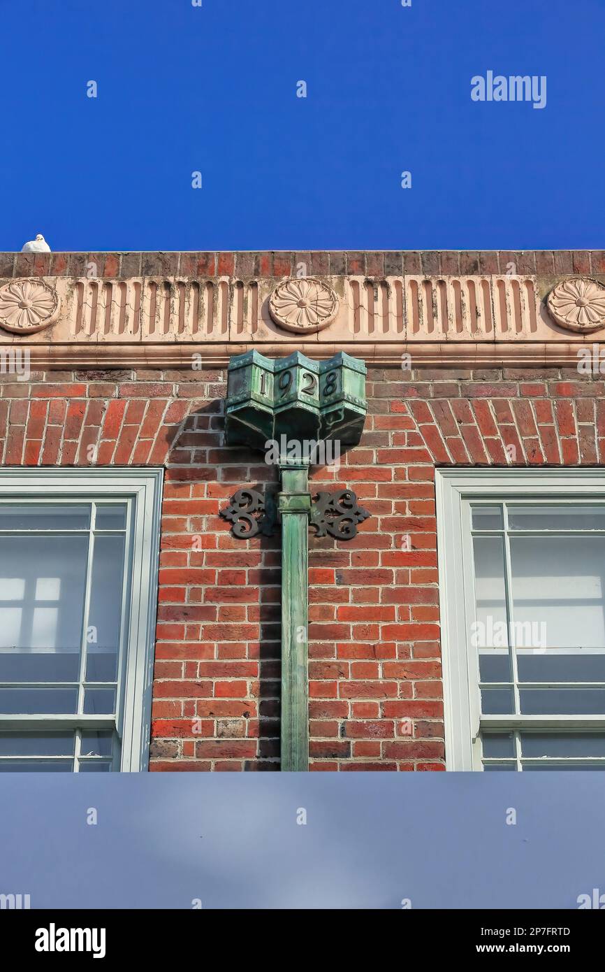 533 Red brick facade with fluted frieze-flower medallions-rusty leader head decoration-AD1928 heritage building in The Corso-Manly suburb. Sydney-AUS. Stock Photo