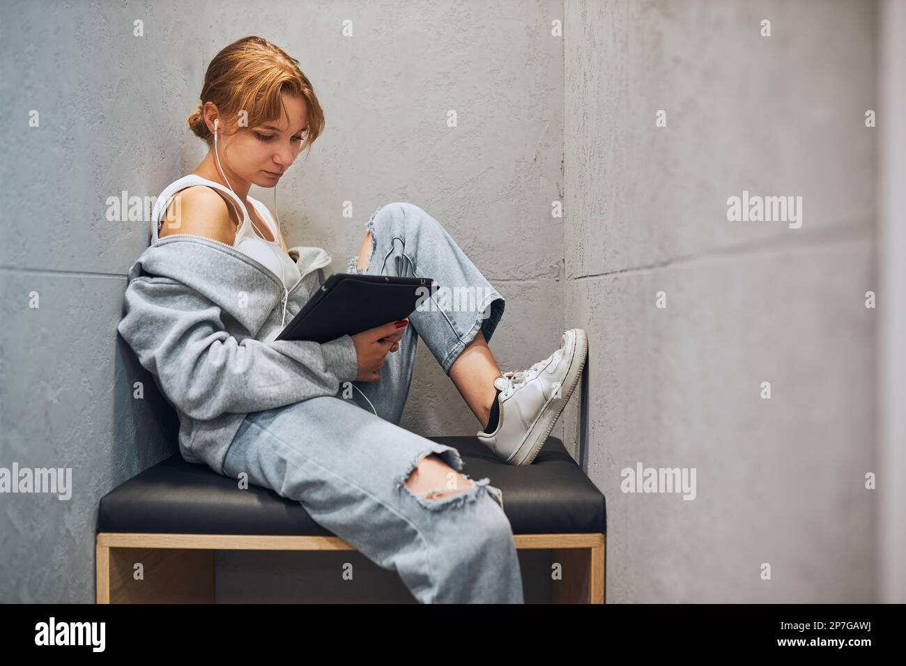 Student learning in university library. Young woman reading e-book using computer tablet. Focused student studying for college exams. Using technology Stock Photo