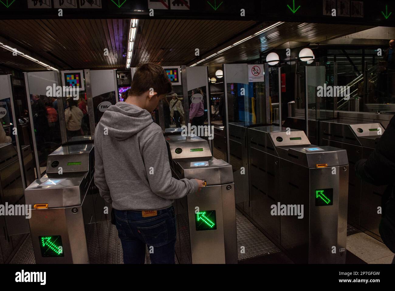 Barcelona,Spain- February 22,2023:A young man introduces his subway ticket at a turnstyle to enter. Stock Photo