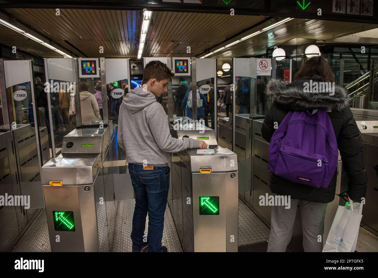 A young man introduces his subway ticket at a turnstyle to enter. Stock Photo