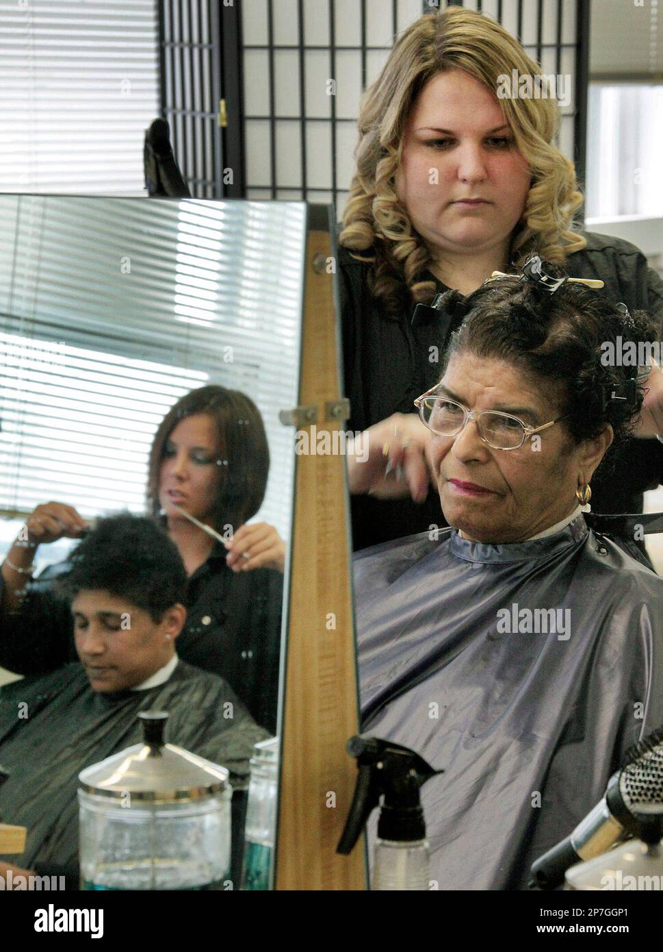 Ashley Sloane, right rear, gives Maria Centeio, right front, a haircut as  fellow LeBaron Hairdressing Academy student Kayla Gallugi, left rear, is  seen reflected in the mirror cutting hair for Sonjia Langford