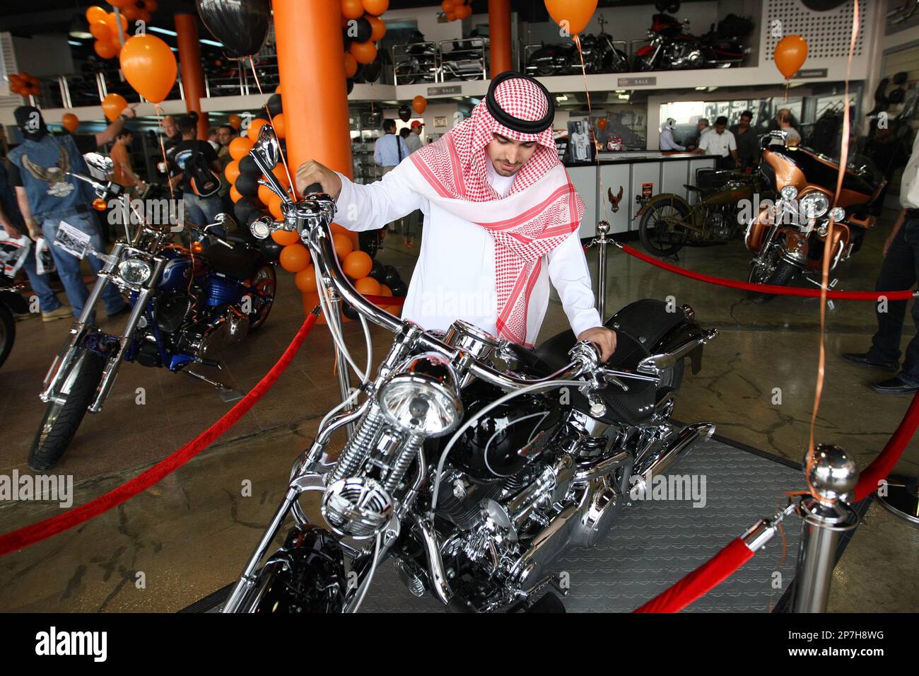 A Saudi man wearing a traditional dress look at a Harley Davidson