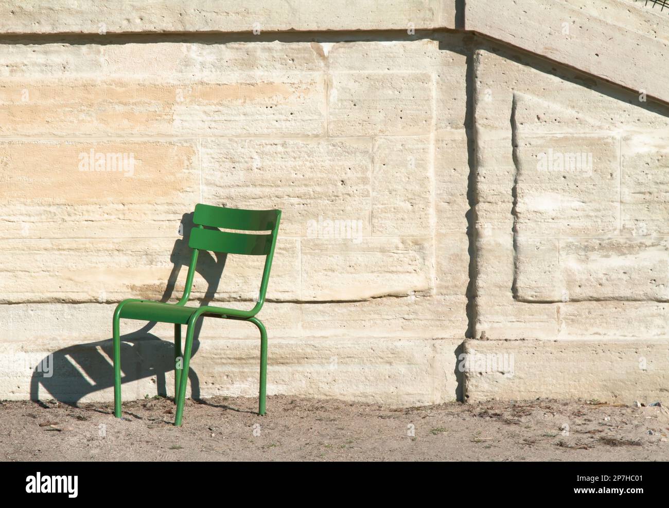 One Empty Green Chair Against A Stone Wall In The Jardin Tuileries, Paris France Stock Photo