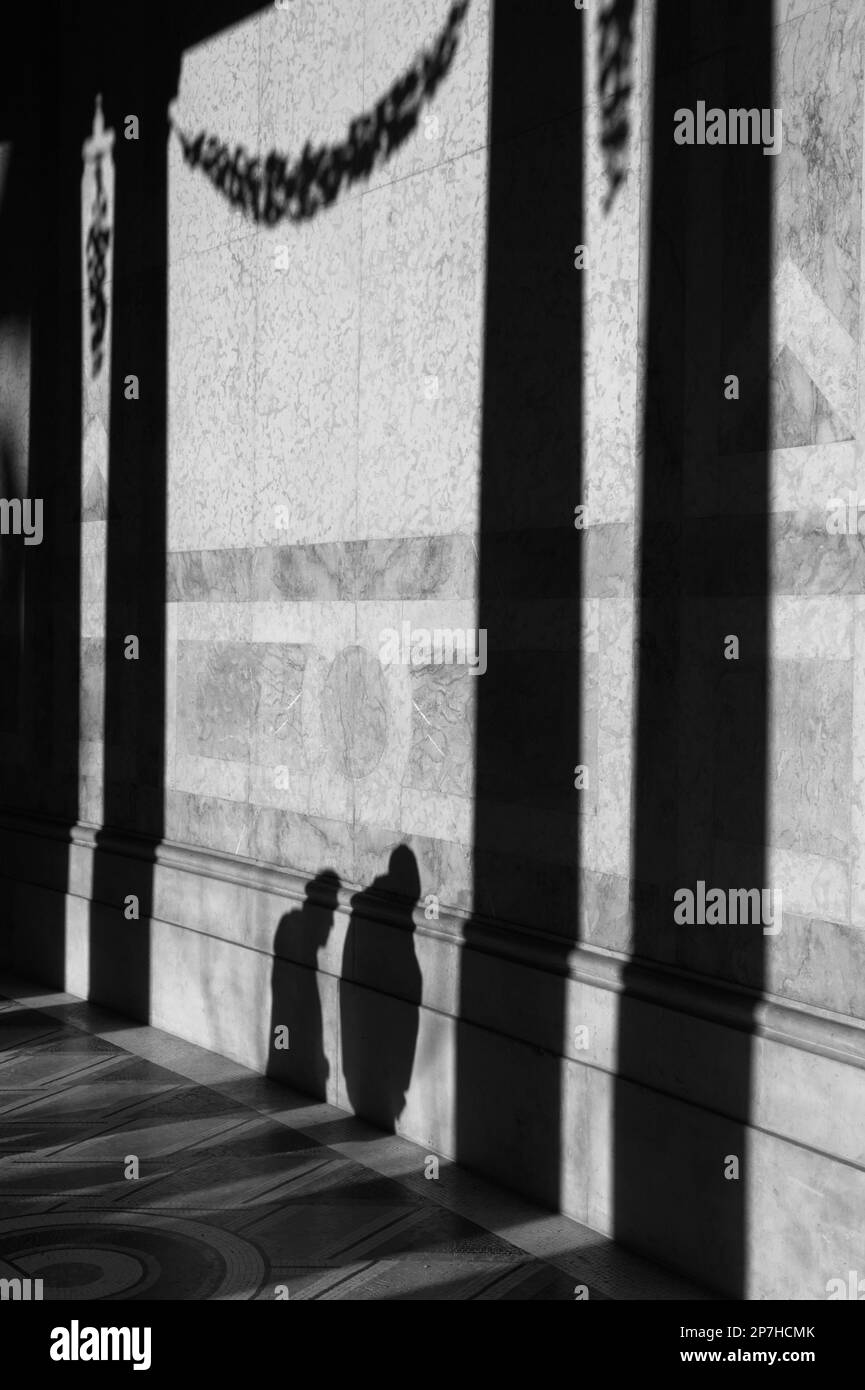 Black And White Image Of The Shadows Of Two People On The Walls Of The Marble Walkway Of The Art Museum Petit Palais Paris France. Stock Photo