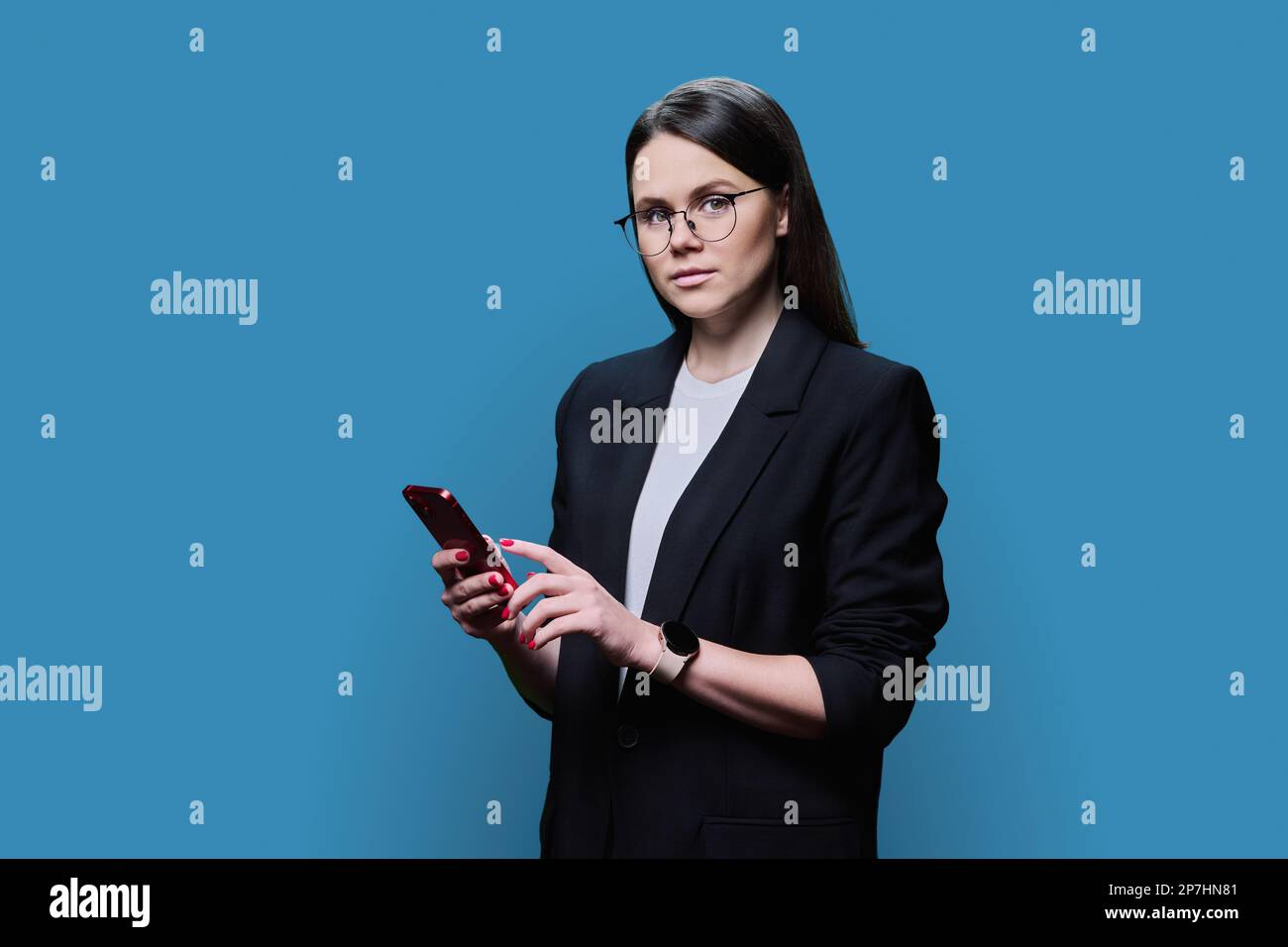Young business woman using smartphone on blue studio background Stock Photo