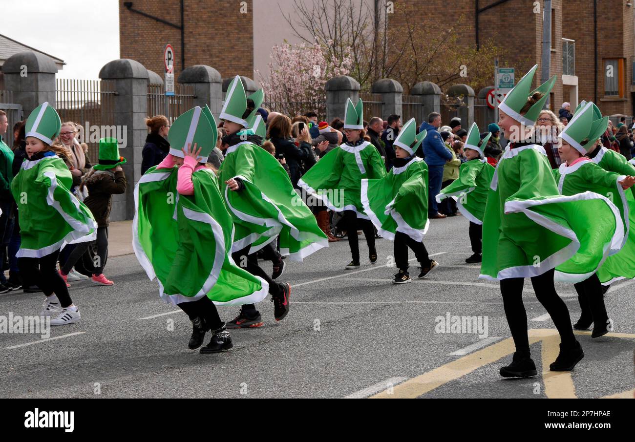 Young people dressed as Saint Patrick, holding onto their hats on a windy day at the  Saint Patrick's Day parade in Wexford, Ireland. 17 March 2017 Stock Photo