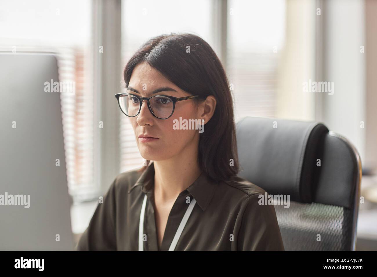 Portrait of focused businesswoman wearing glasses using computer at workplace Stock Photo