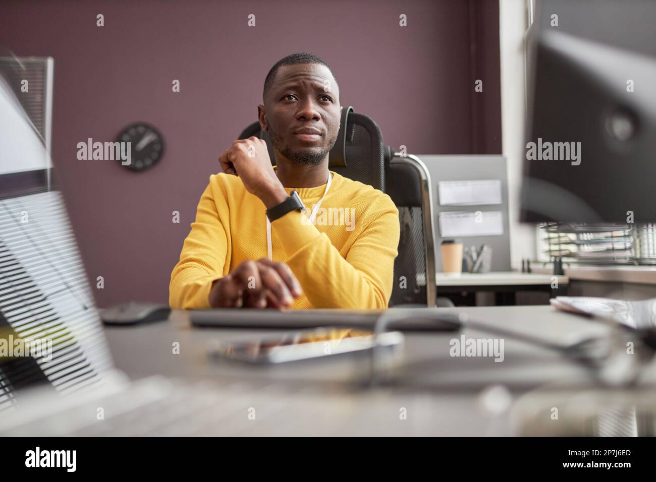 Low angle portrait of focused black man using computer in IT development office, copy space Stock Photo
