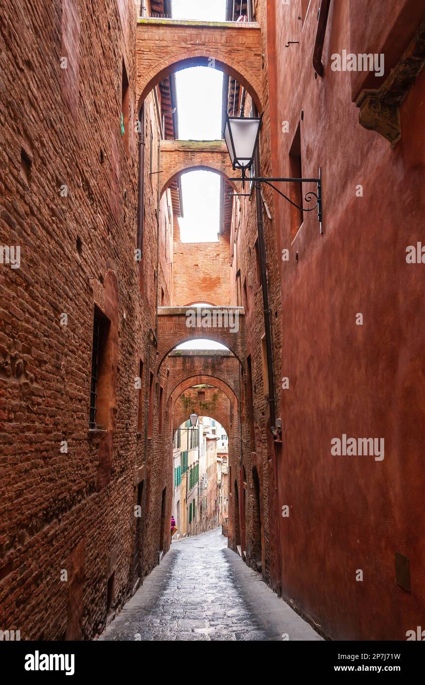 Narrow old street with several upstairs passages, in Siena, Tuscany, Italy Stock Photo