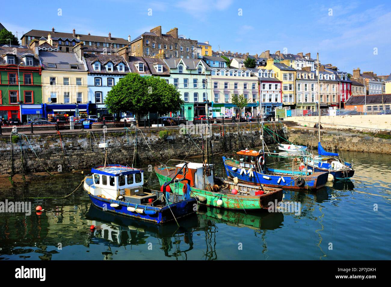 Old boats with colorful harbor buildings in background in the port town of Cobh, County Cork, Ireland Stock Photo