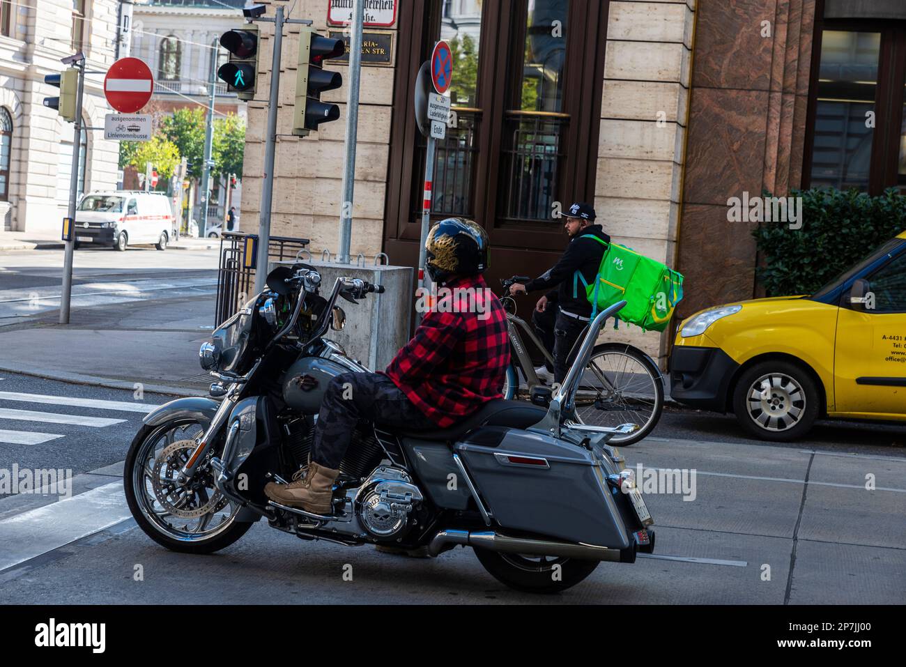 Vienna, Austria - October 18, 2022: Biker on a Harley Davidson and bike delivery man on the street standing at a traffic light in Vienna, Austria Stock Photo