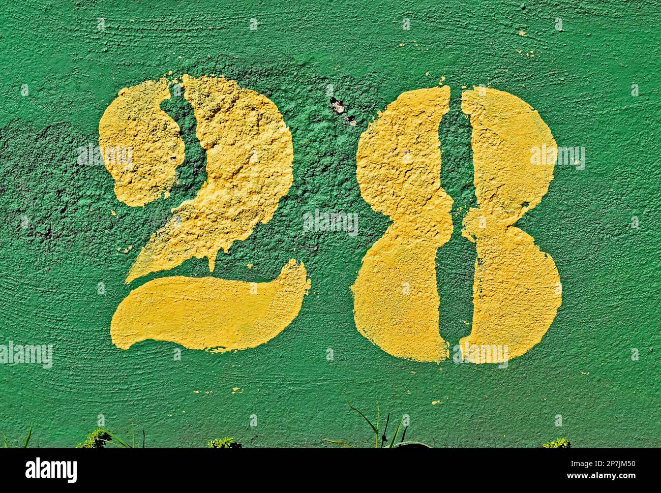 Number 28 painted in yellow on a green wall Stock Photo