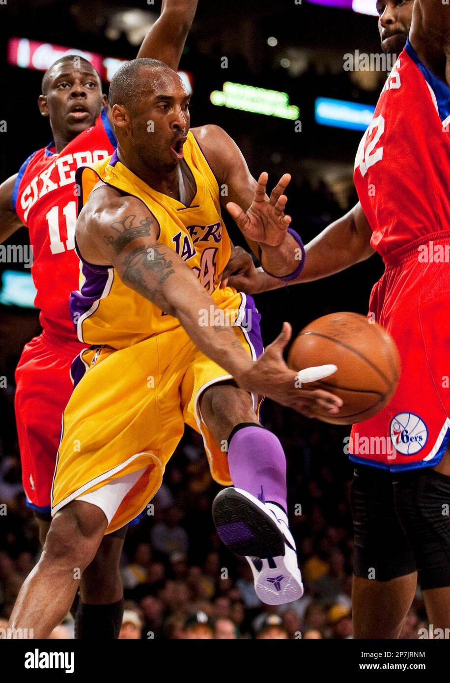 Los Angeles Lakers' Kobe Bryant passes the ball while being guarded by Philadelphia 76ers' Jrue