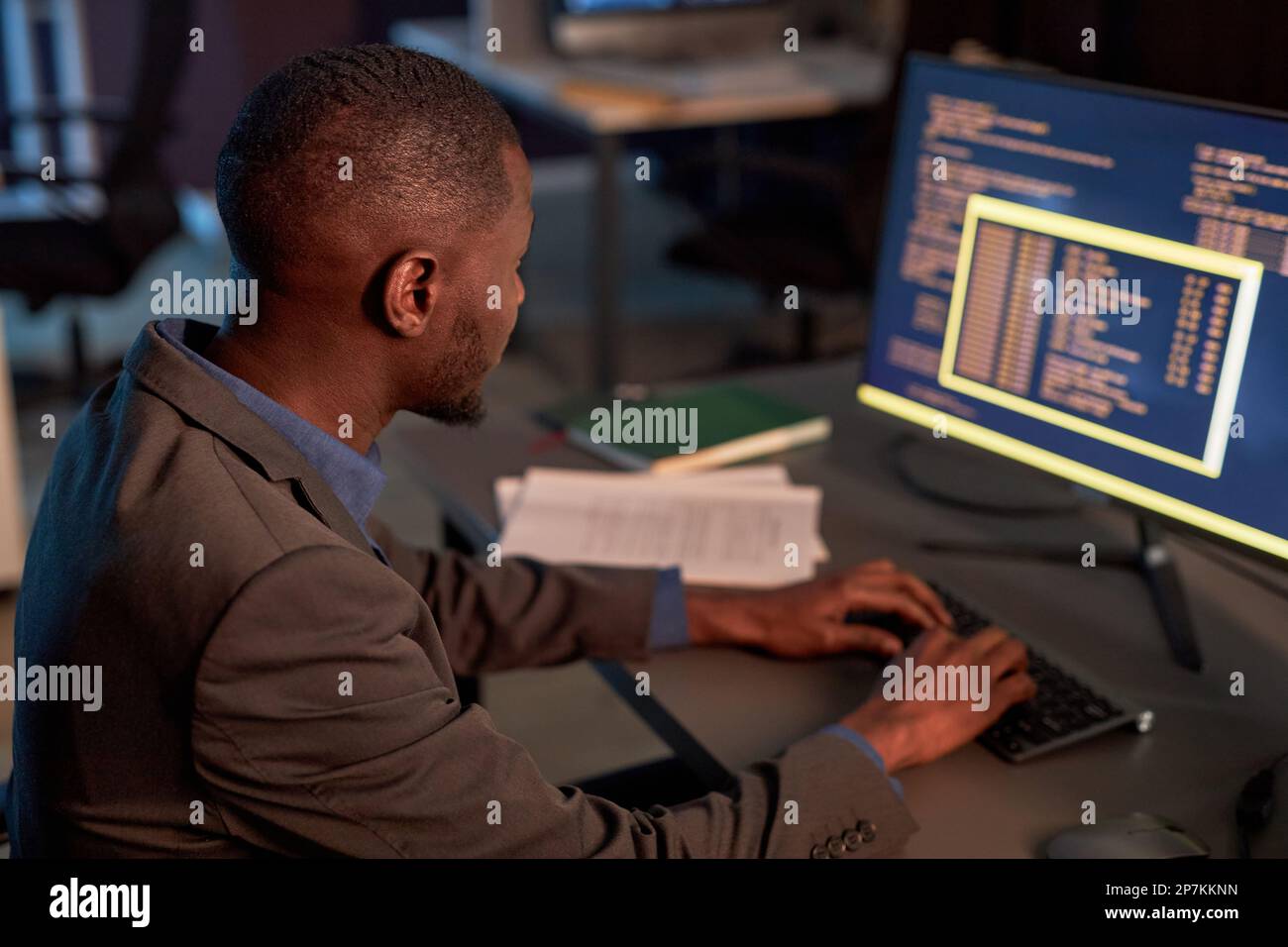 High angle view at black IT developer wearing suit and using computer while working on data security project in office Stock Photo