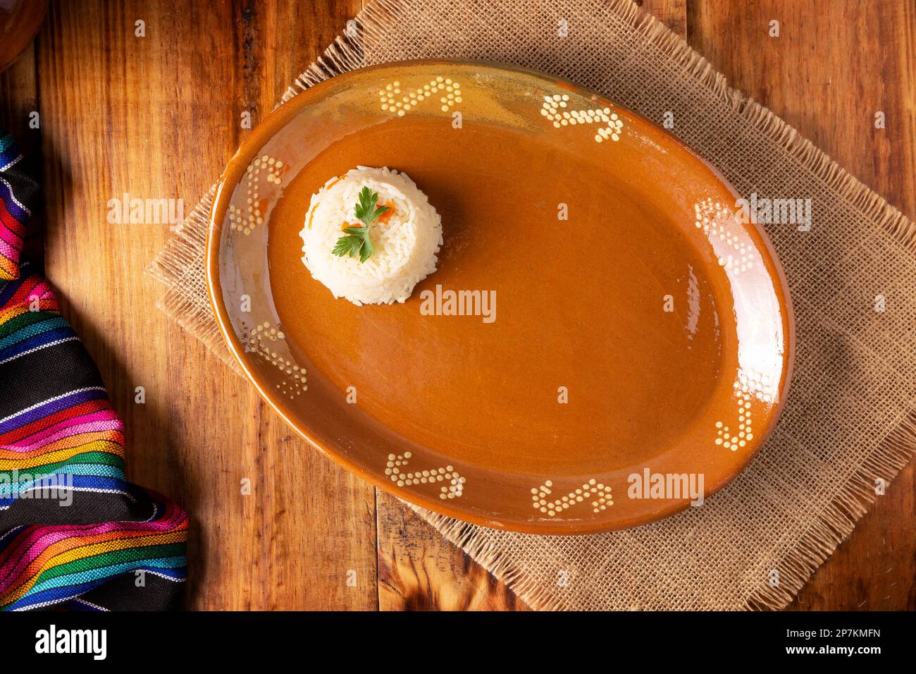 Cooking background with half empty mud dish, mexican typical fabric on rustic wooden table. Table top view with copy space. Stock Photo