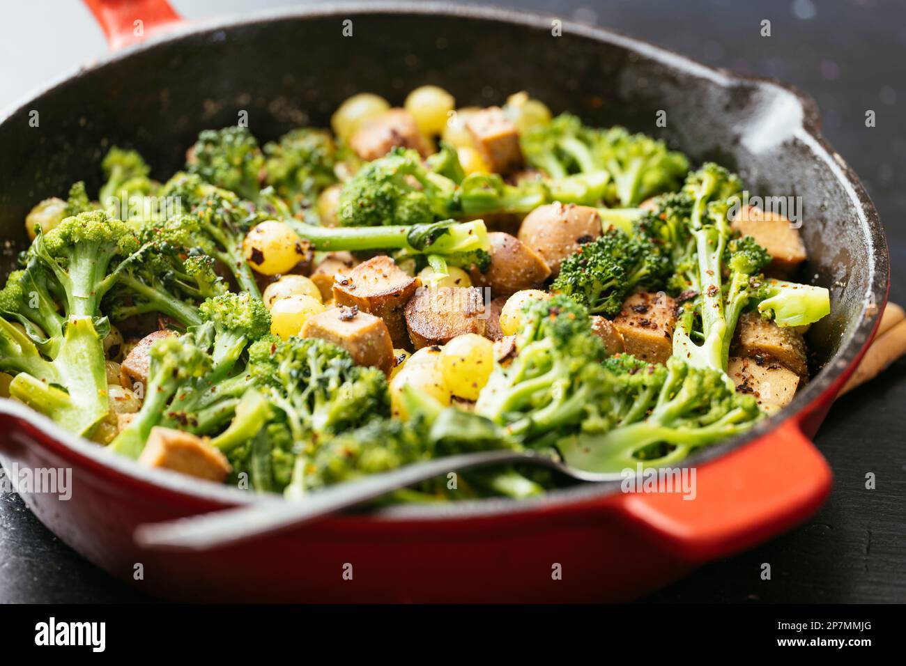 Vegan Sausage with Broccoli and Grapes in a cast iron pan Stock Photo