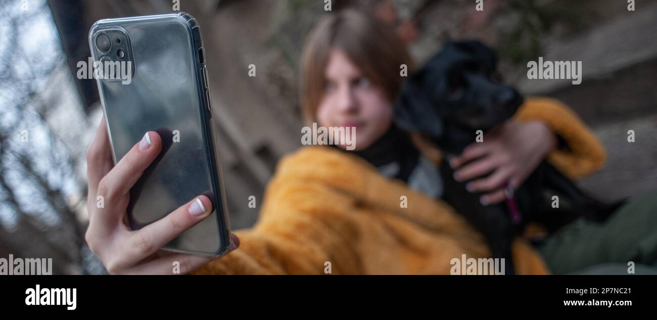 Influencer, teenage girl with a black dog taking a selfie with her ...